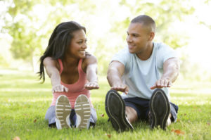 Woman and man outside stretching while sitting and looking at one another smiling